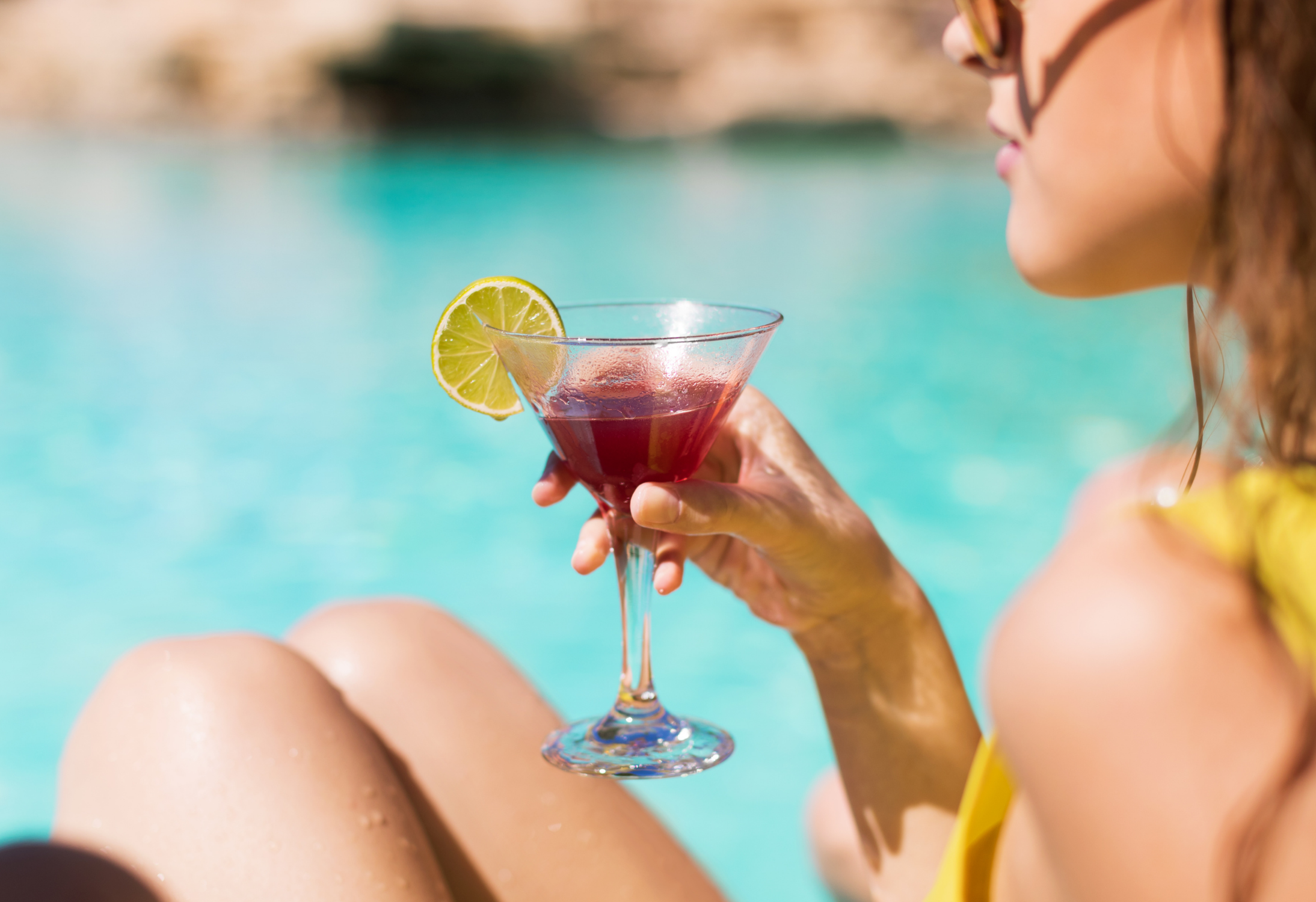 Frau mit Cocktail in der Hand am Pool, die heimlich Quiet Vacationing macht