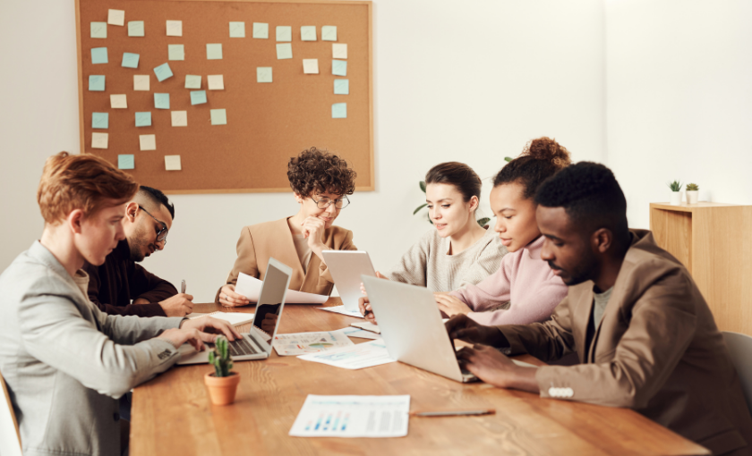Ein diverses Team arbeitet konzentriert am Tisch zusammen, um durch Culture Add die Gefahr von Groupthink im Unternehmen zu vermeiden.